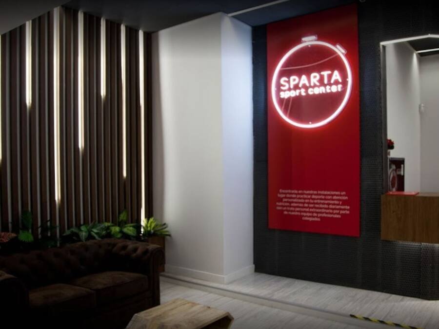 A modern interior with a red sign reading "SPARTA sport center" and a wooden reception desk.