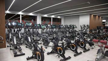 Ein Fitnessraum mit mehreren Laufbändern und stationären Fahrrädern, die in Reihen angeordnet sind.
