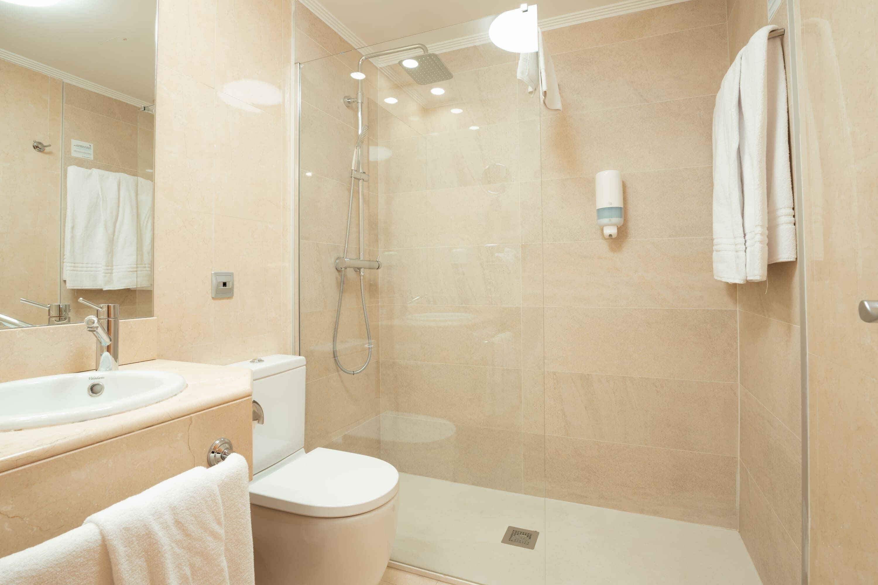 A modern bathroom with a glass-enclosed shower, a toilet, and a sink.