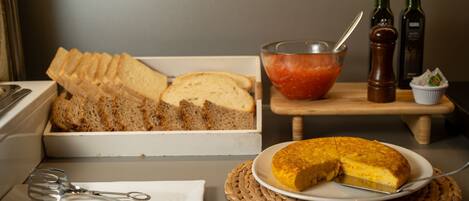 A kitchen counter with a loaf of bread, a bowl of tomato sauce, and two bottles of olive oil.
