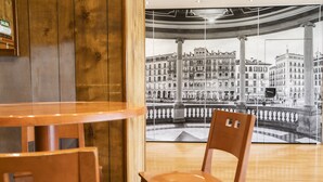 Een houten interieur met uitzicht op een historisch Europees stadsgezicht door een groot raam.