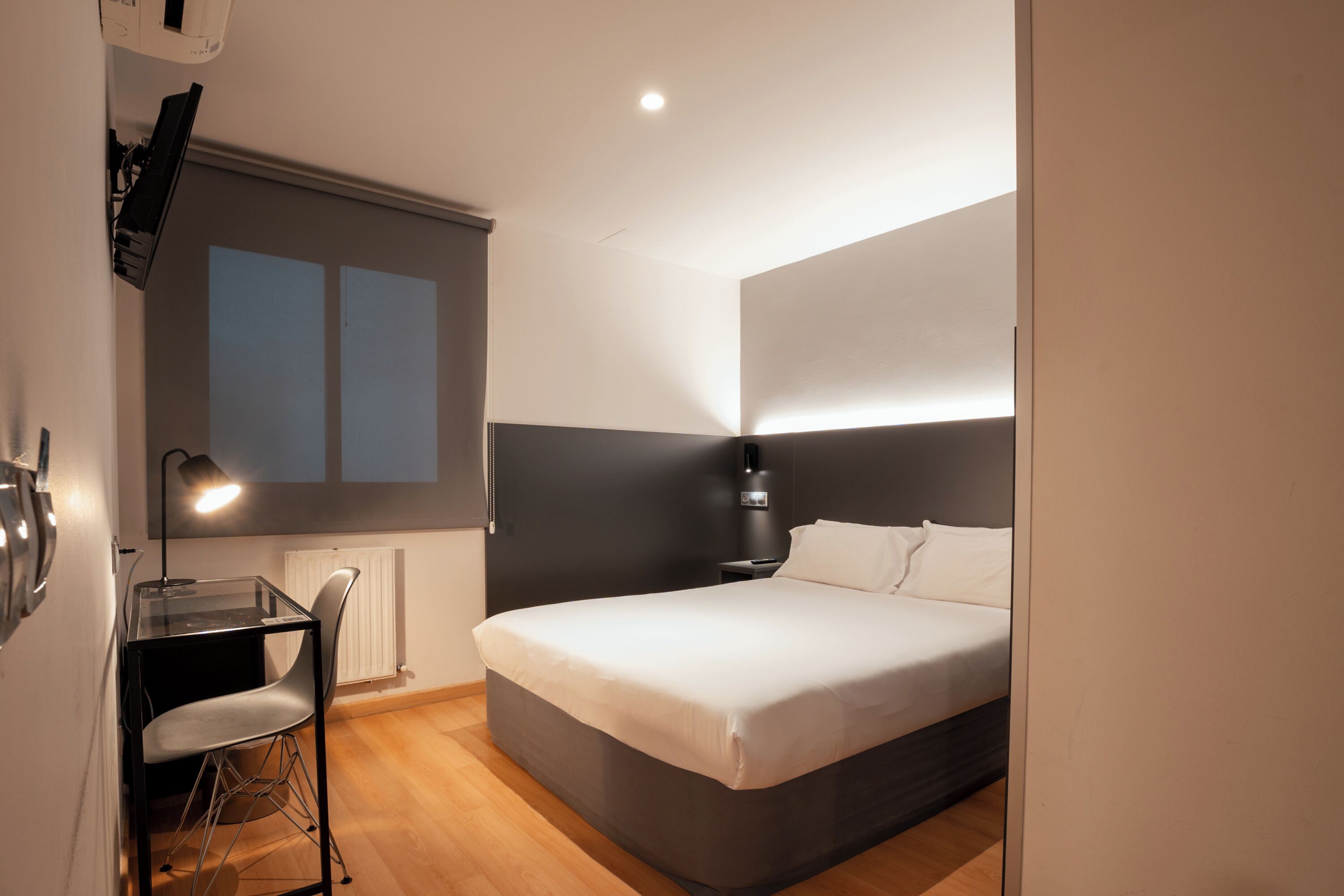 A modern bedroom with a bed, a desk, and a chair.