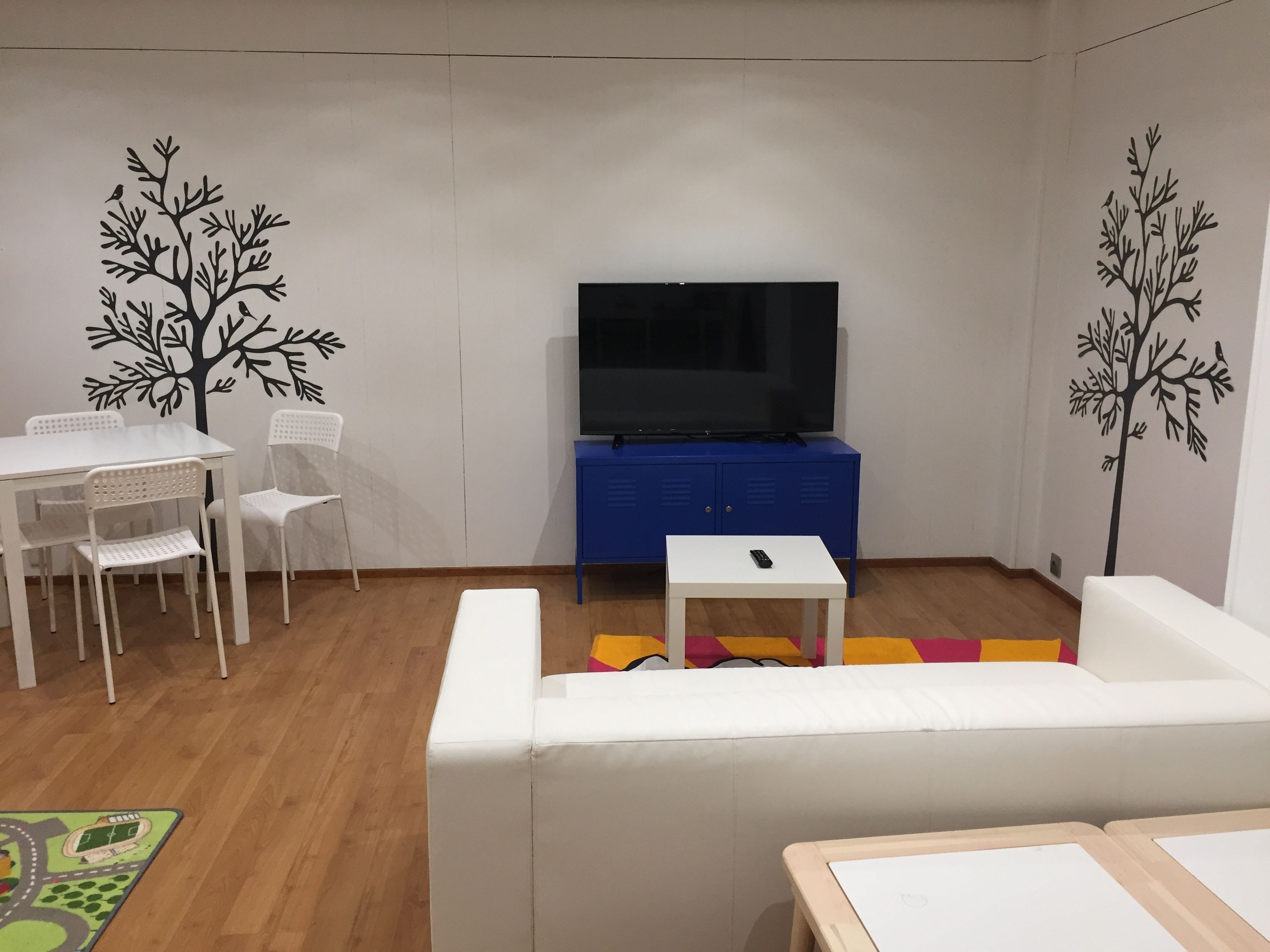 A living room with a white sofa, a small white table, a blue cabinet, and a TV.