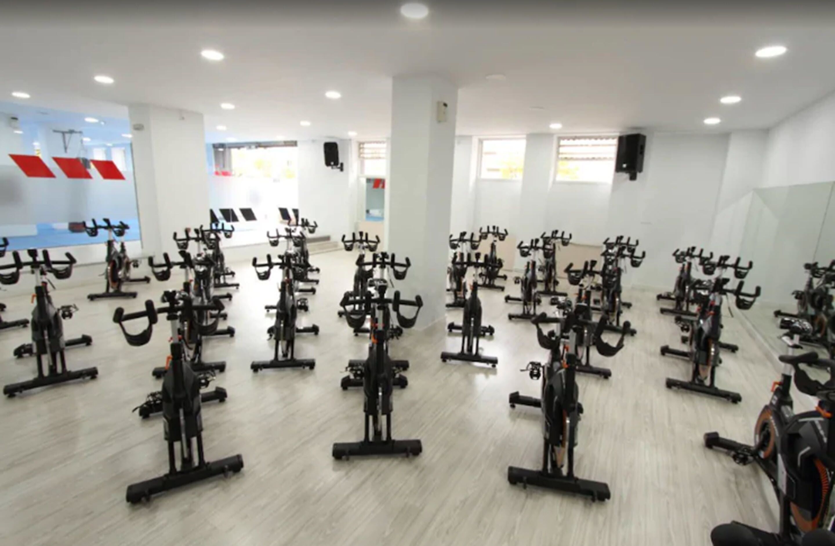 Un gimnasio amplio con varias bicicletas estáticas dispuestas en filas.
