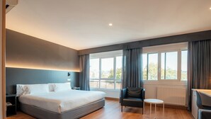Een moderne hotelkamer met een groot bed, een bureau, een stoel en een bijzettafeltje.