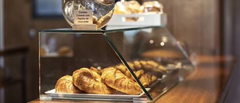 Una vitrina con pasteles y un tarro etiquetado como 'Cookies Caseras con Pepitas de chocolate'.