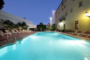 Une piscine avec des chaises longues et un bâtiment en arrière-plan.