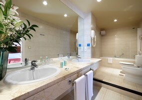 Un baño moderno con dos lavamanos, un espejo grande y zona de ducha.