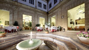 A spacious courtyard with a fountain, tiled steps, and outdoor seating areas.