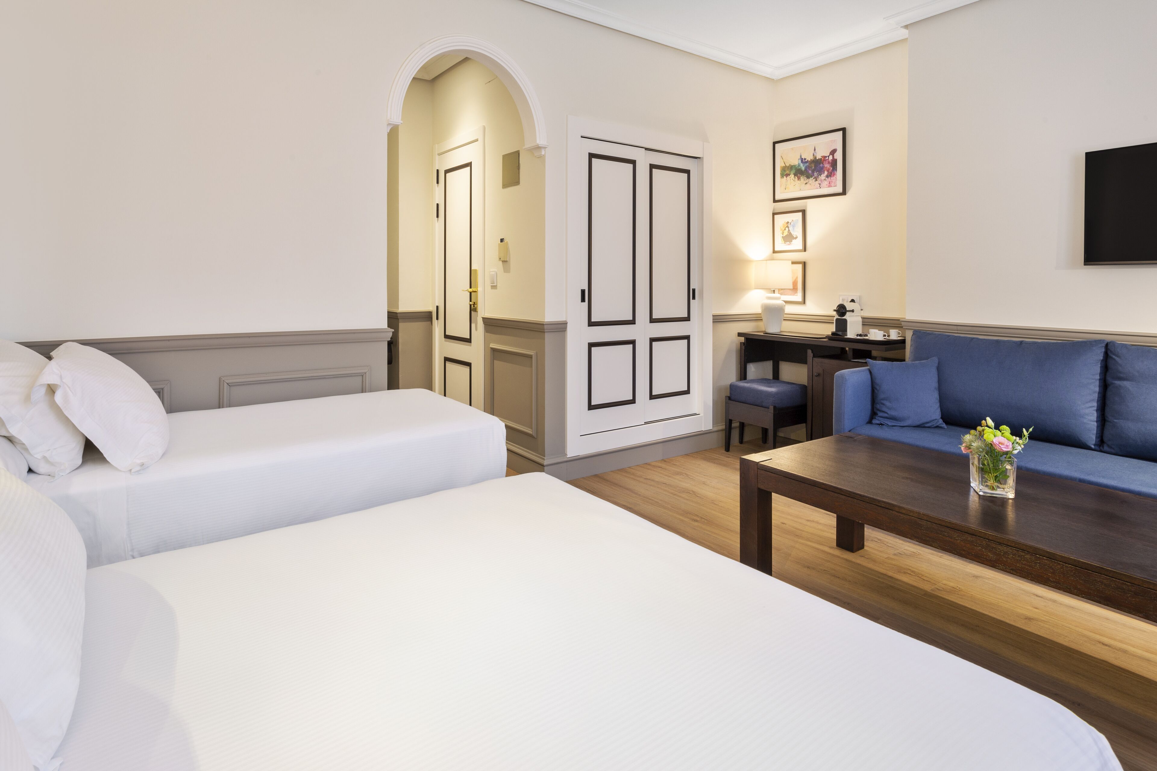 Una habitación de hotel con dos camas, un sofá, un escritorio y una mesa de centro.