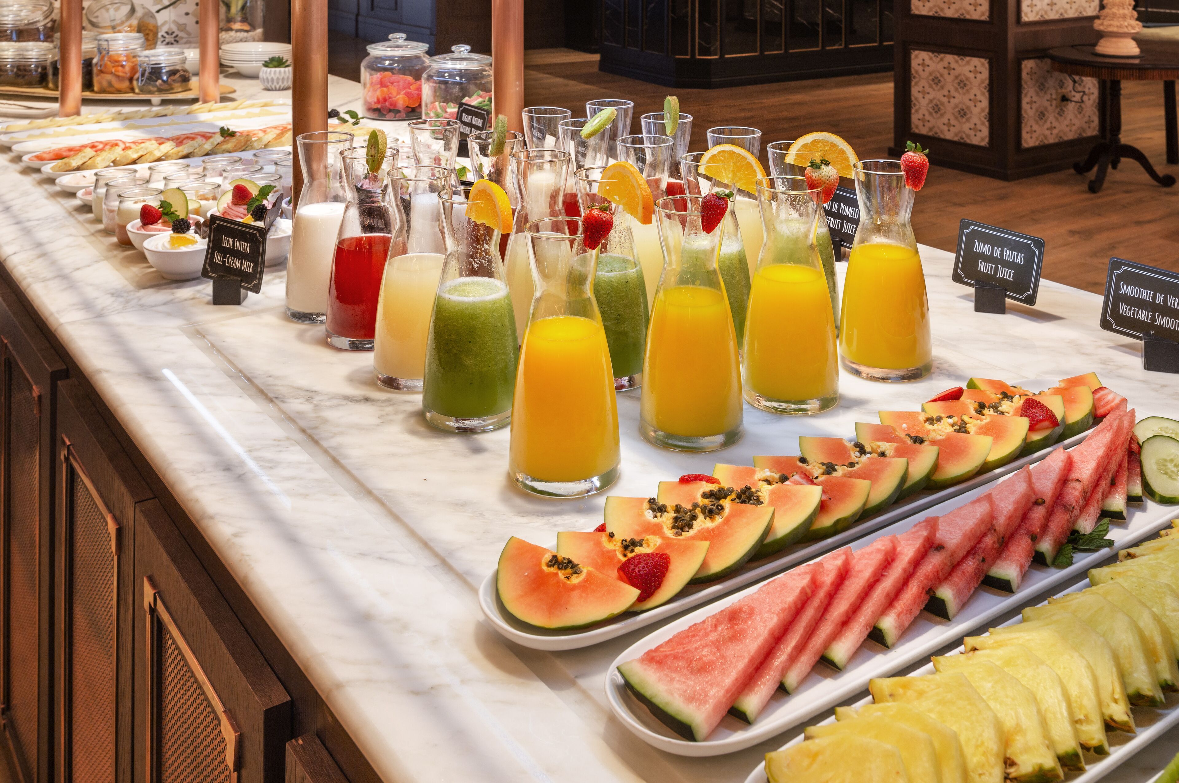 A buffet with various fruit slices and a selection of fruit juices.