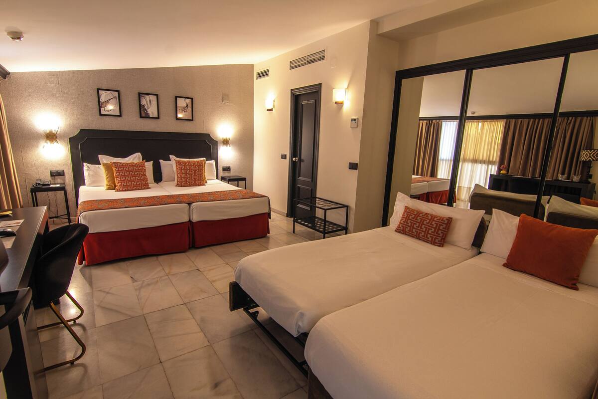 Une chambre d’hôtel avec deux lits, un bureau et une chaise.