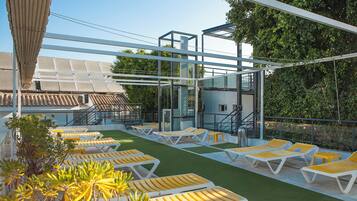 Een seizoensgebonden buitenzwembad en ligstoelen