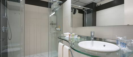 A modern bathroom with a glass shower enclosure, a glass sink, and a large mirror.