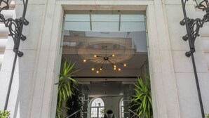 Entrada de un edificio con escaleras, el número 24 y una lámpara araña moderna.