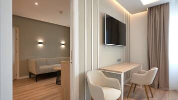 Una sala de estar moderna con un sofá, un televisor montado en la pared y un comedor con mesa y sillas.
