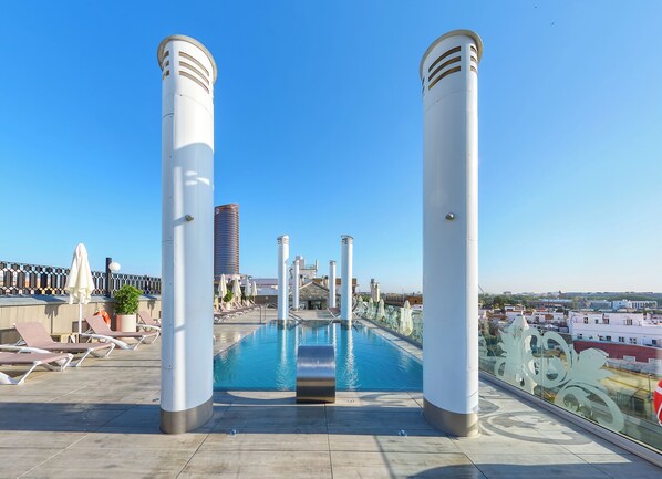 Een buitenzwembad, parasols bij het zwembad en ligstoelen