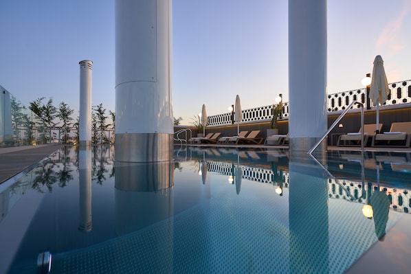 Una piscina al aire libre de temporada, sombrillas, tumbonas