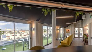 Un interior moderno con ventanas amplias, un balcón con mobiliario exterior y vistas a la ciudad.