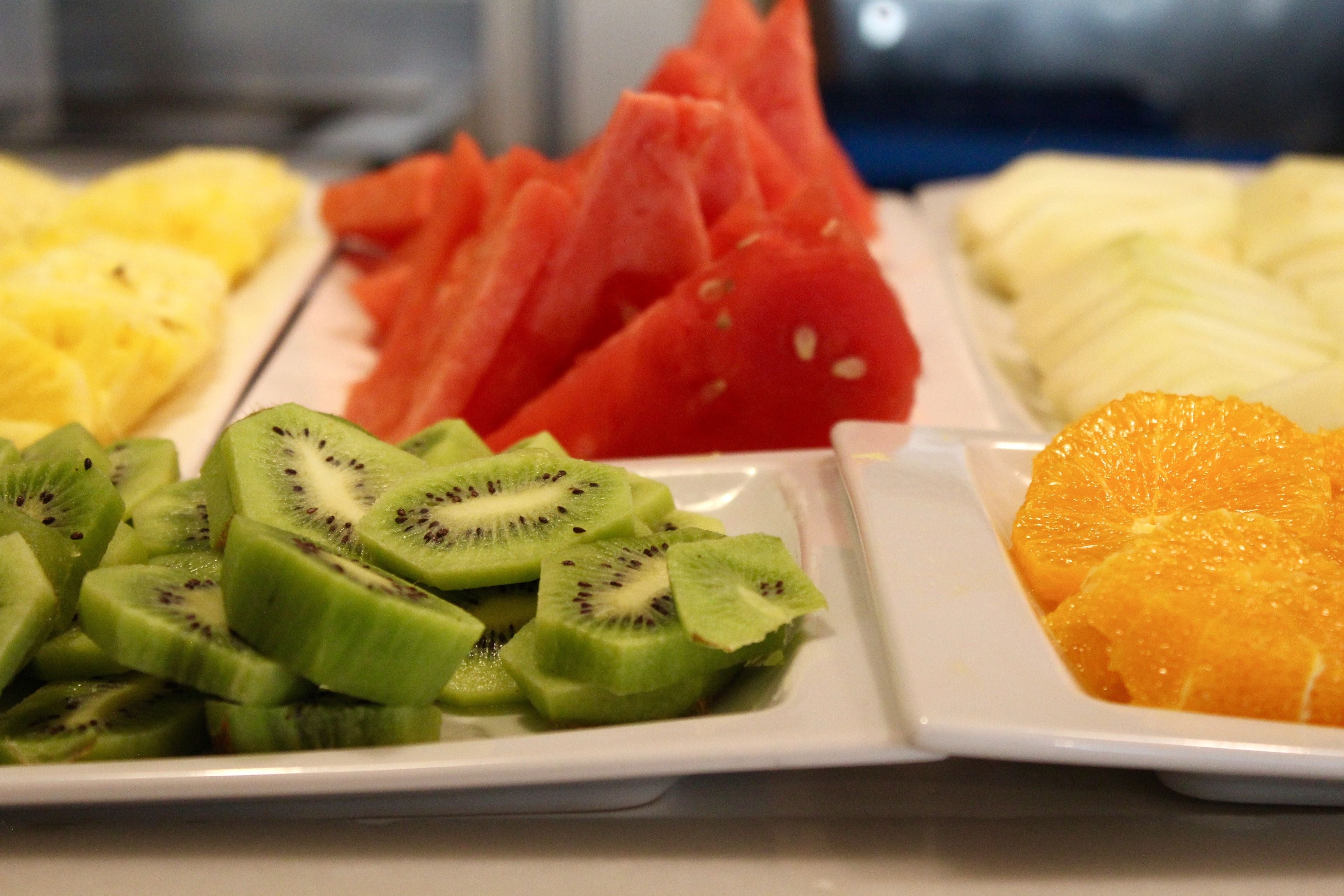 Una bandeja de frutas con kiwi, sandía, piña y naranja en rodajas.