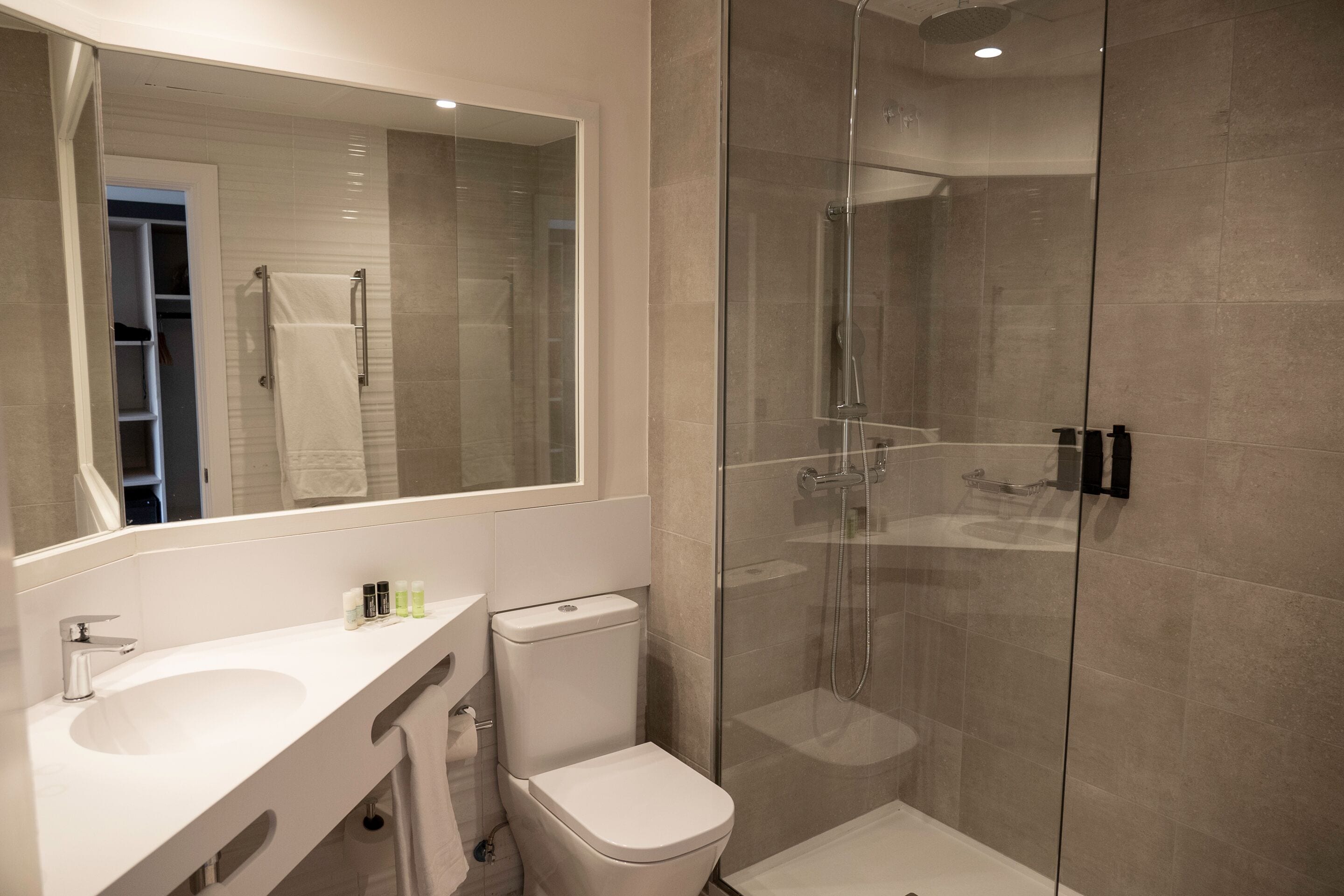 A modern bathroom with a glass-enclosed shower, a white sink, and a toilet.
