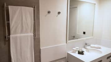 A modern bathroom with a white sink, mirror, and towel rack.
