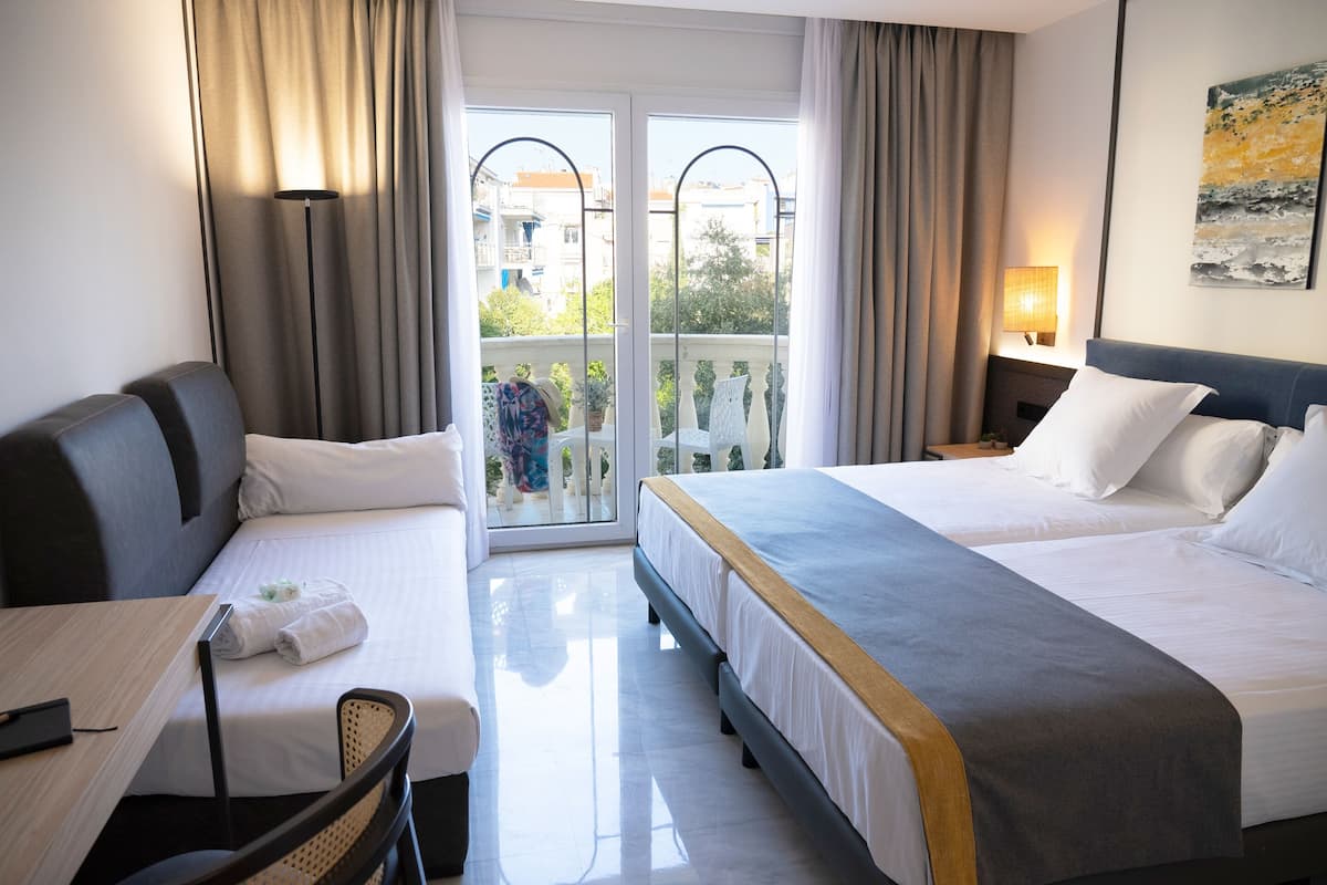 A hotel room with two beds, a desk, and a chair.
