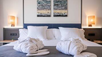 Habitación de hotel con una cama bien tendida, dos lámparas fijadas a la pared y dos cuadros abstractos sobre la cama.