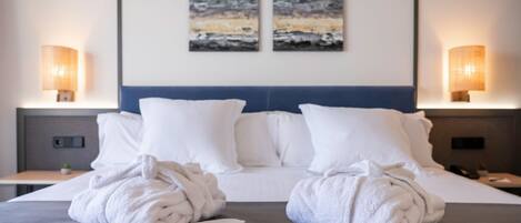 A hotel room with a neatly made bed, two wall-mounted lamps, and two abstract paintings above the bed.