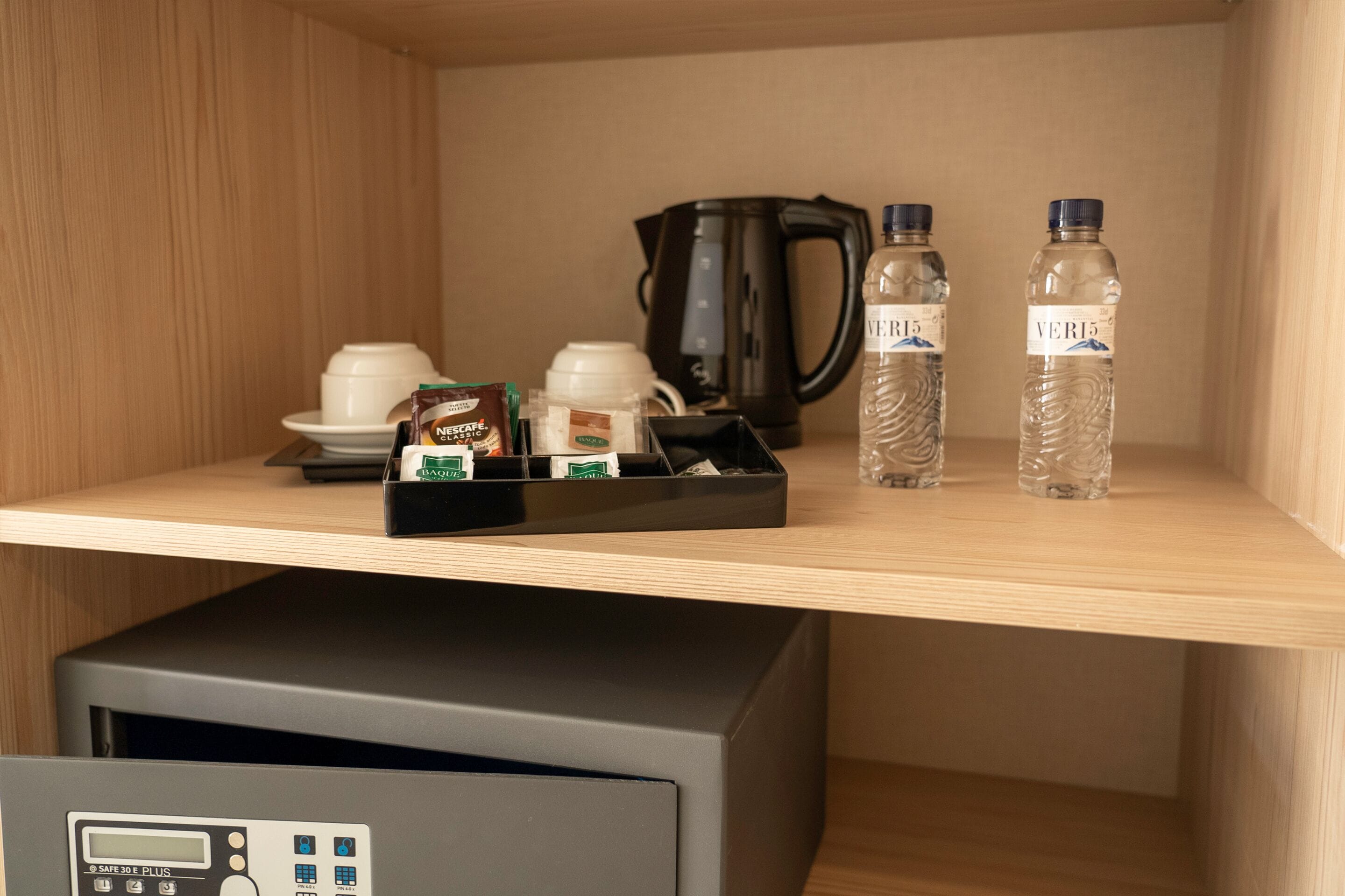 Hotellihuoneen minibaarissa on kahvia, teetä ja pullovesiä, sekä kahvinkeitin ja pieni jääkaappi.