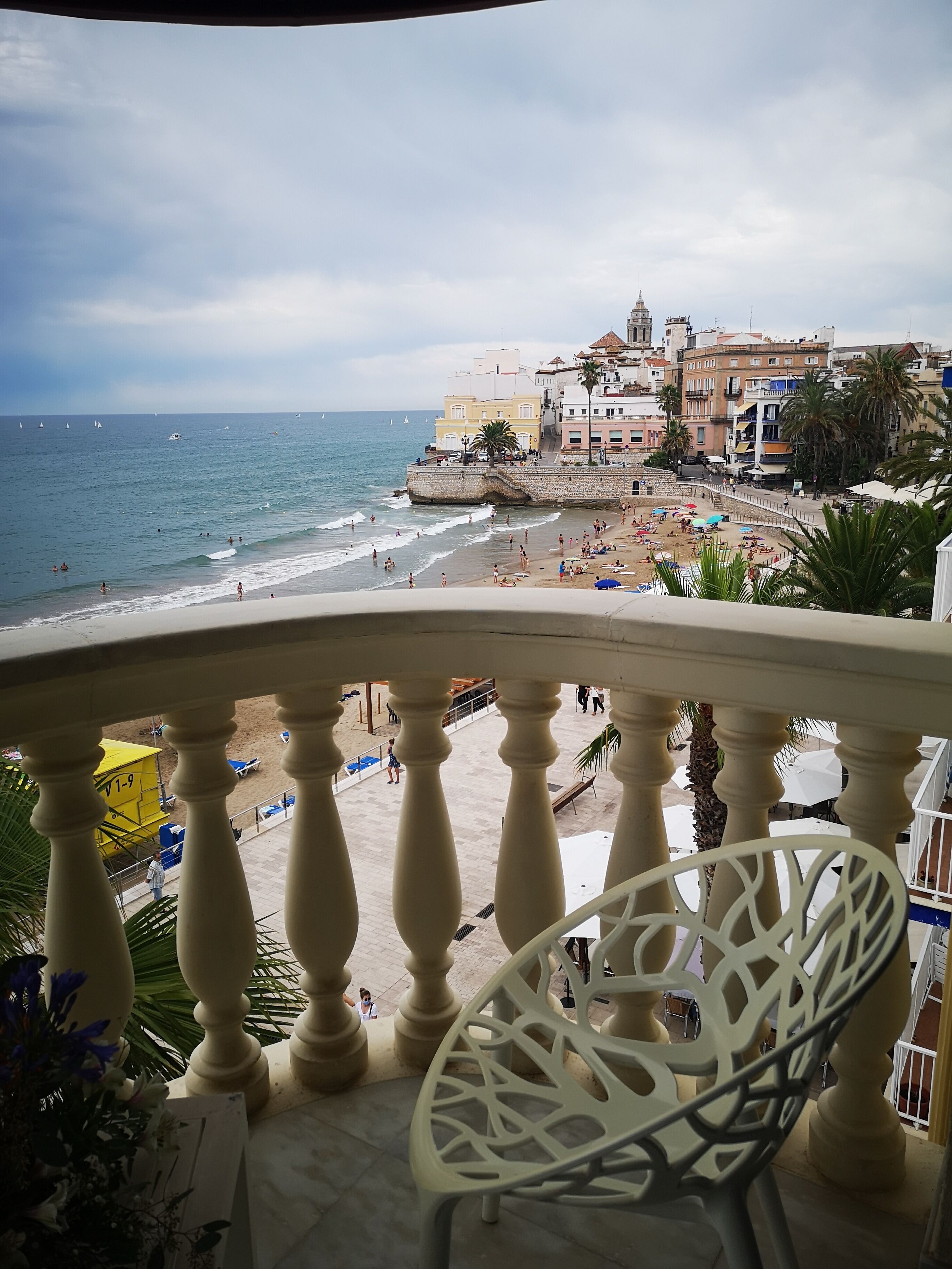 A balcony with a view of a beach and a historic building.