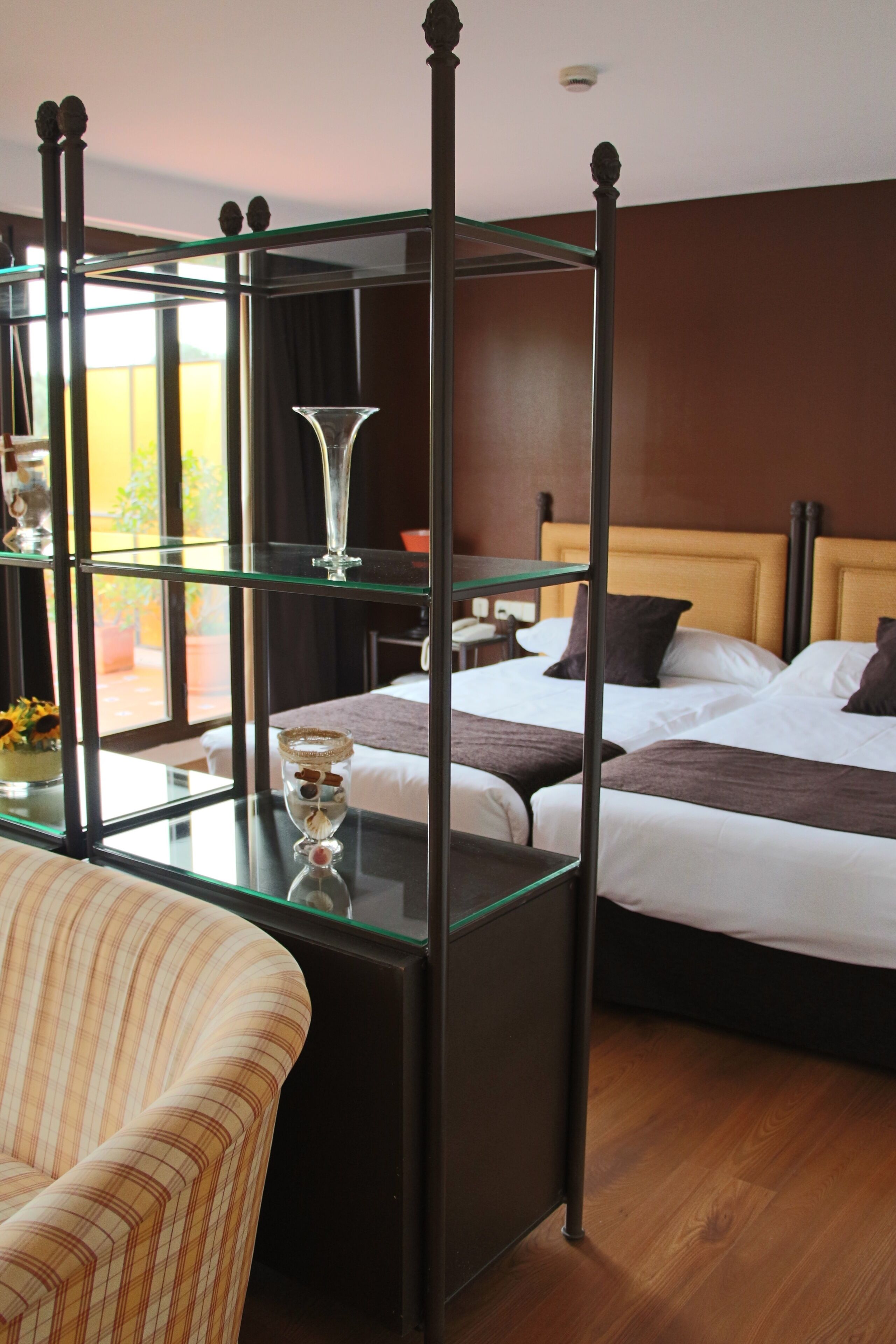 A hotel room with a four-poster bed, a glass coffee table, and a striped armchair.