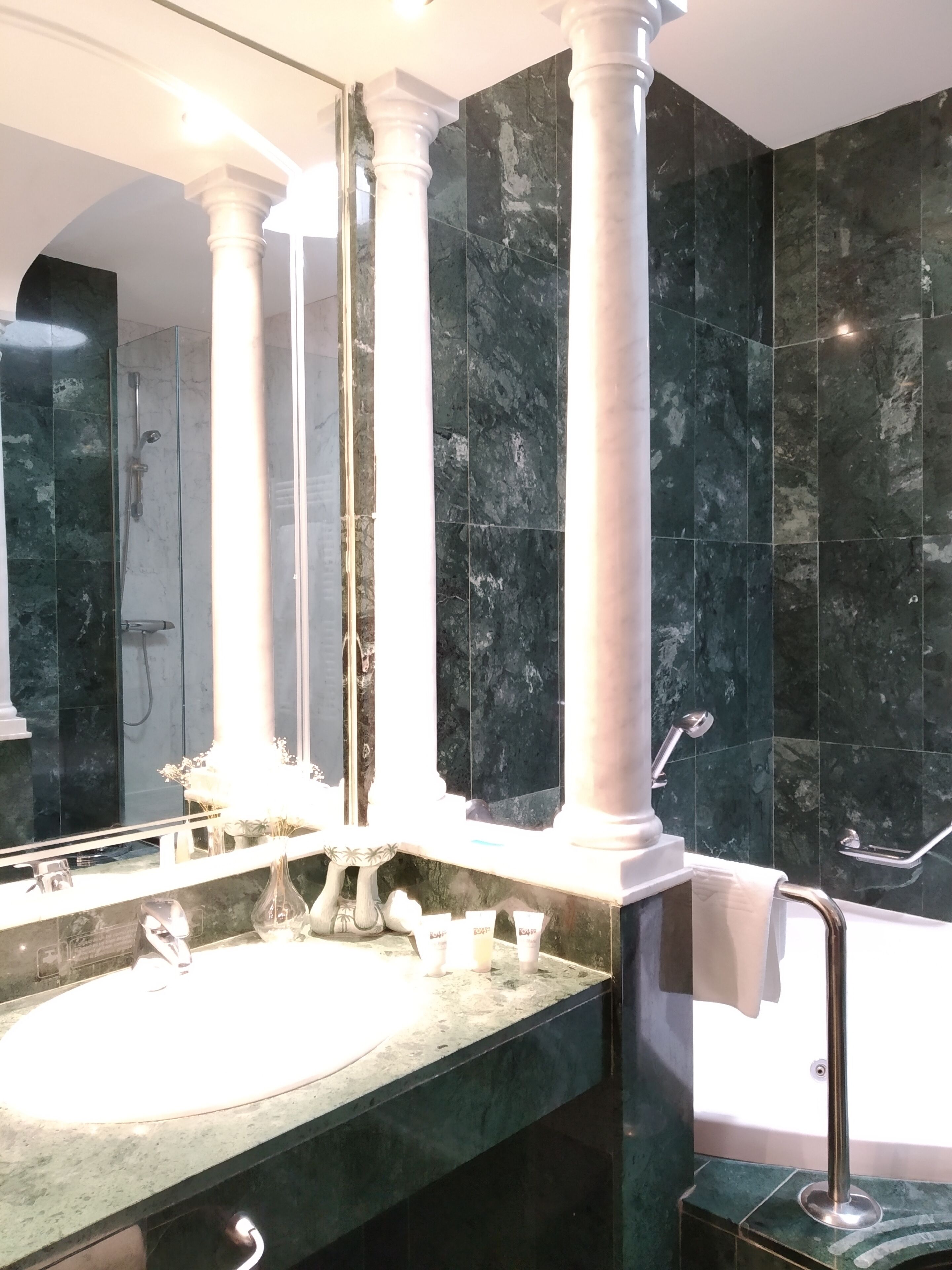 Un baño con un espejo grande, un lavamanos y una zona de ducha.