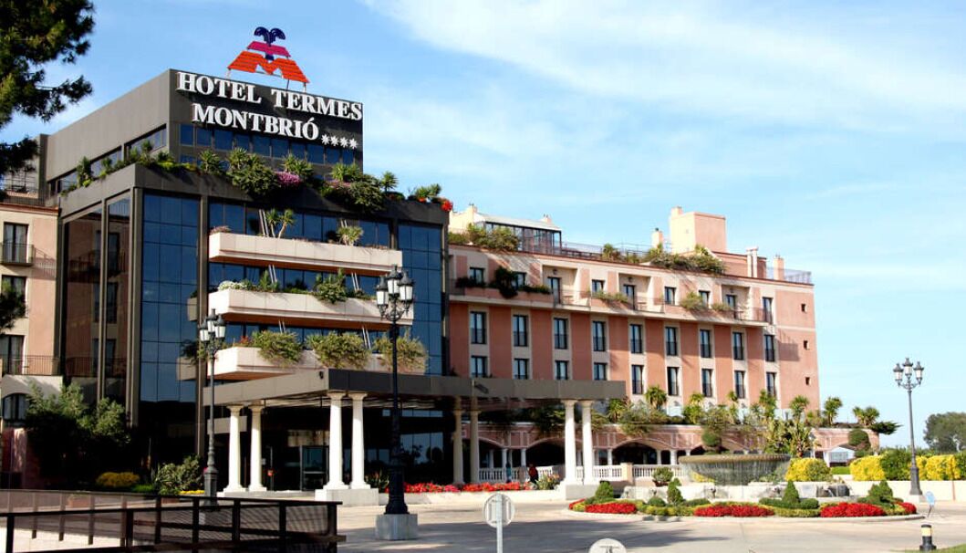A hotel with a modern facade, a prominent sign, and a landscaped entrance area.