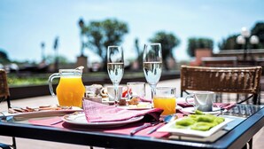 Una mesa de desayuno con una jarra de jugo de naranja, dos vasos de agua y platos de comida.