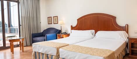 A hotel room with a large bed, a chair, a desk, and a view of the outdoors.
