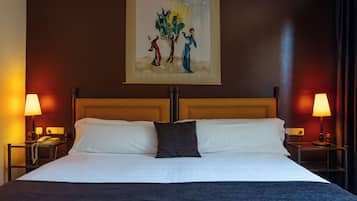 Una camera d'albergo con un letto grande, due comodini con lampade, un quadro appeso alla parete e una testata del letto in legno.