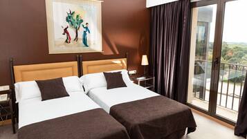 Habitación de hotel con dos camas, un cuadro en la pared, una mesita de noche, una lámpara y un balcón con vistas.