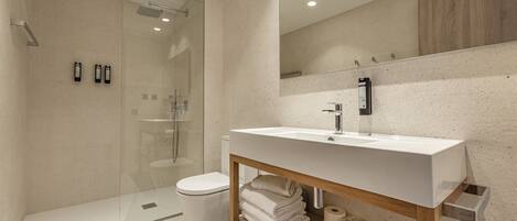 Un baño moderno con cabina de ducha de vidrio, lavamanos blanco y tocador de madera.