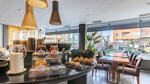 A breakfast bar with various food items and a view of the city. - Hotel Astari (Tarragona)