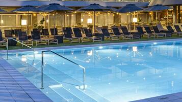 Una piscina al aire libre, sombrillas, sillones reclinables de piscina