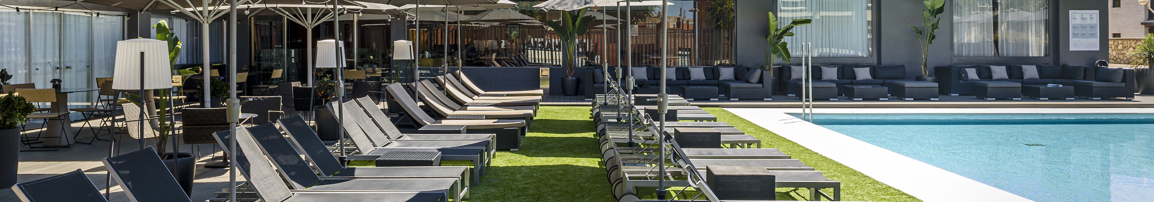 A poolside area with sun loungers, umbrellas, and a pool.