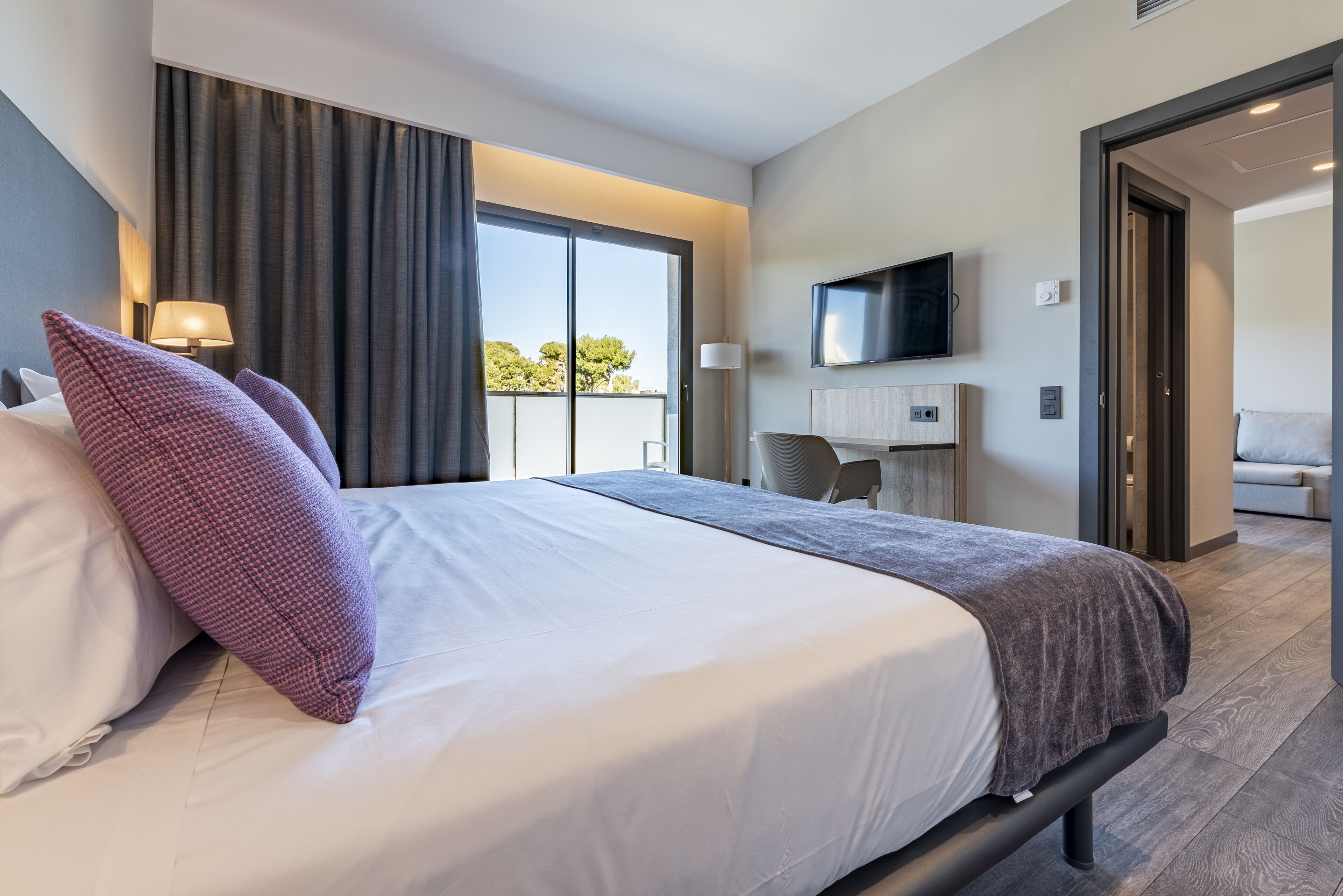 Habitación de hotel moderna con una cama grande, un televisor de pantalla plana, un escritorio y vistas al exterior.