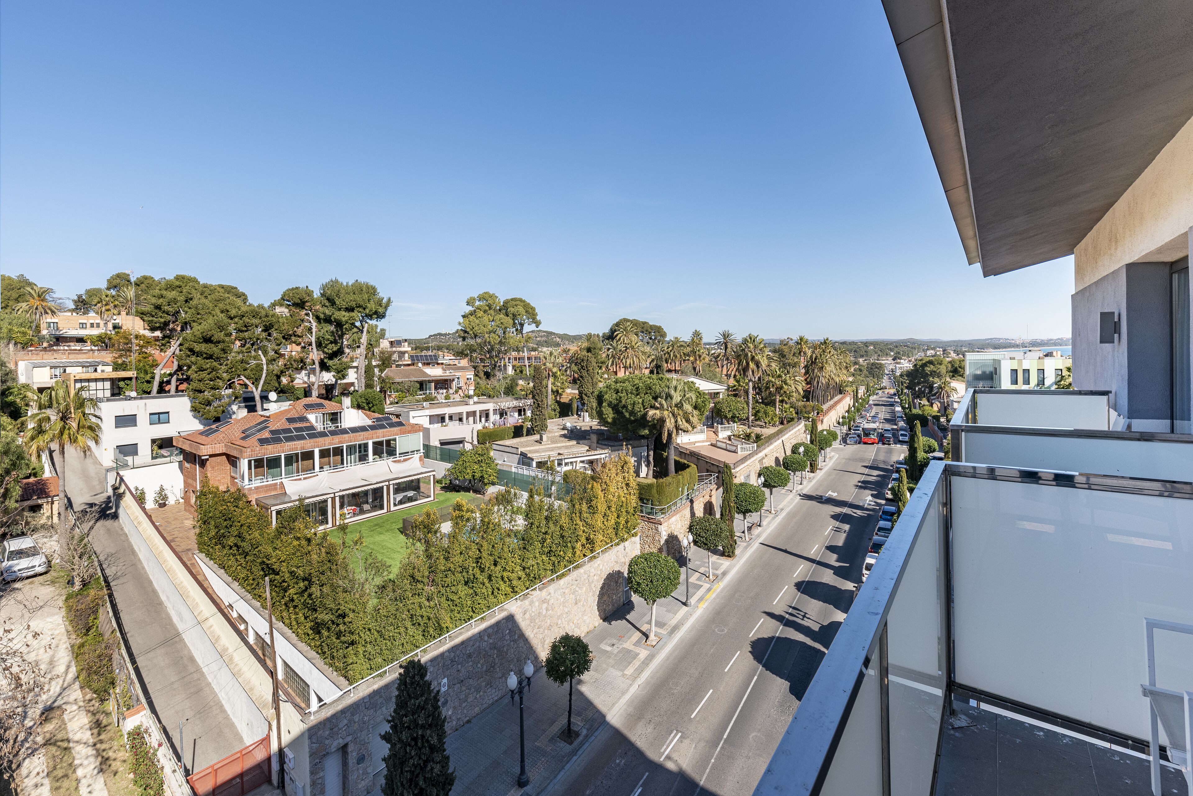 Zona residencial con casas modernas, una calle y un cielo azul despejado.