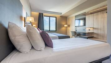 A modern hotel room with a large bed, a desk, and a TV.