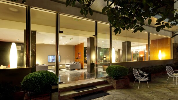 A modern hotel lobby with glass doors, a reception area, and a seating area with chairs and a sofa. - Hotel Astari (Tarragona)