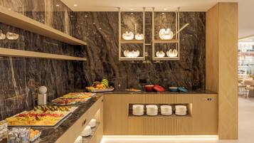 Un moderno montaje tipo buffet con paredes de mármol, diversas opciones de comida y platos ordenados.