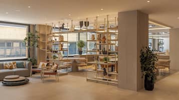 Un interior moderno con un sofá, sillas, una mesa y un estante decorativo con plantas.