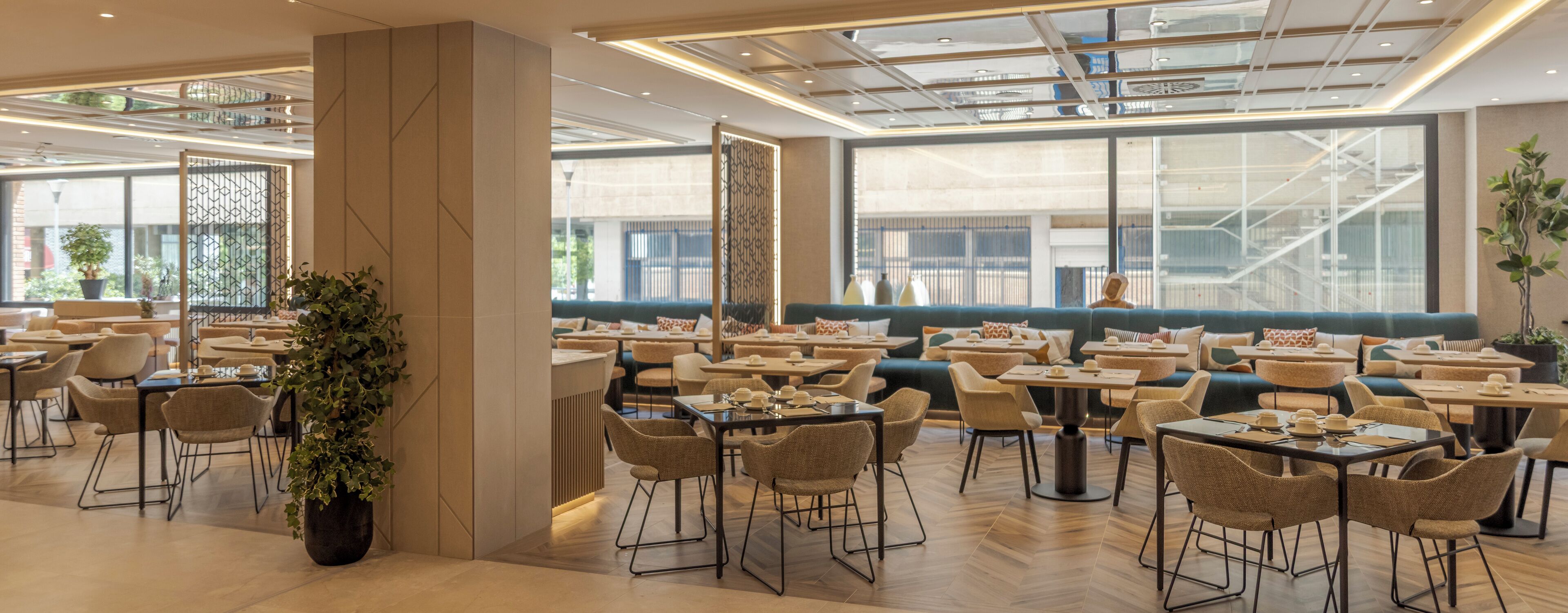 Un comedor moderno con varias mesas y sillas, ventanas amplias y vistas al exterior.