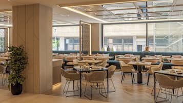 Un comedor moderno con varias mesas y sillas, ventanas amplias y vistas al exterior.
